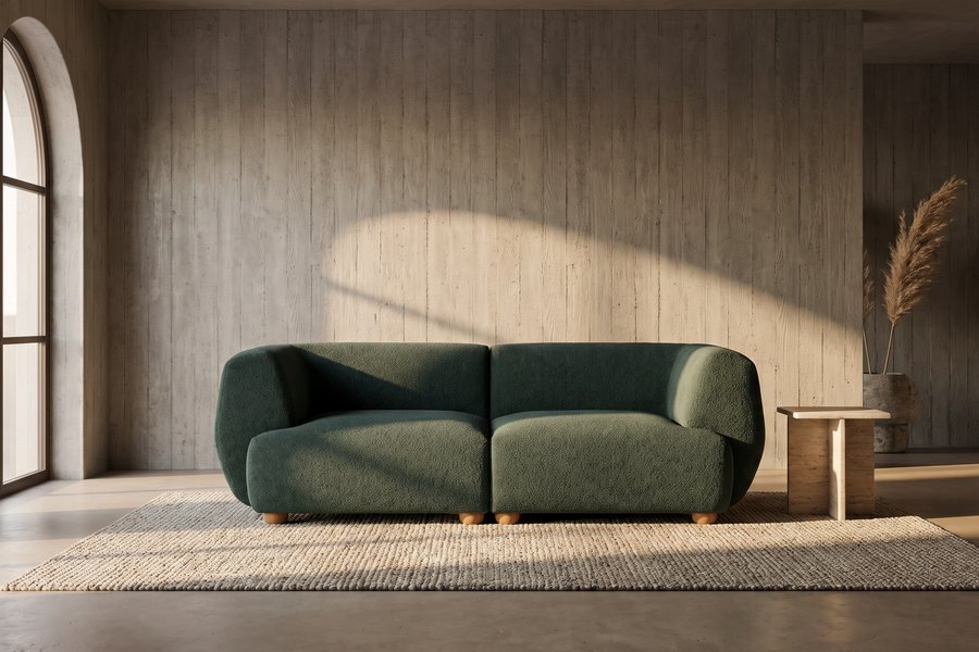 Geschwungenes Bouclé-Sofa in Salbeigrün in einer soft-brutalistischen Lounge mit Betonwänden