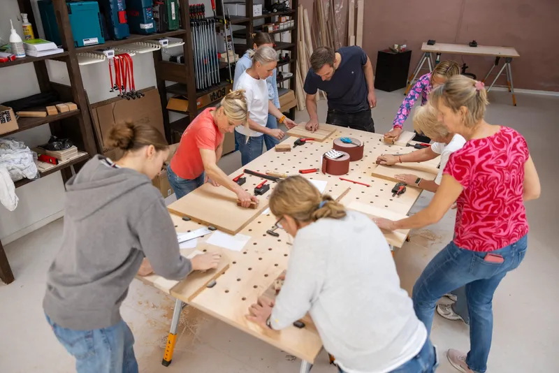 Teilnehmende schleifen und bauen gemeinsam Holzstücke im Holzworkshop mit Henrik Sand