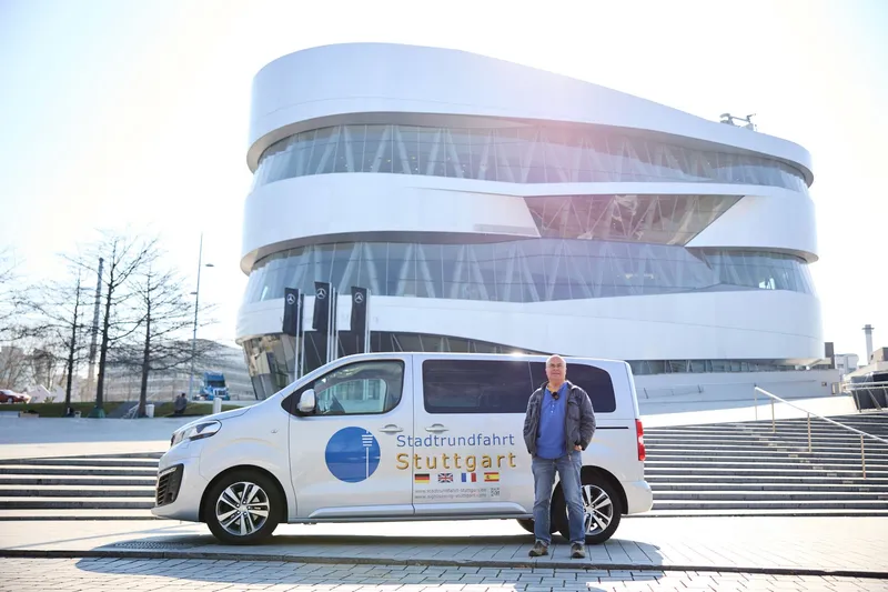 Stadtrundfahrt-Guide Anselm Vogt steht vor seinem Fahrzeug am Mercedes-Benz Museum in Stuttgart